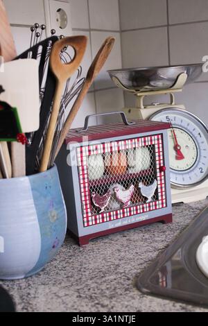 Cozy country kitchen with vintage egg storage box, rustic utensils, and retro scale, creating a warm farmhouse-style atmosphere. Stock Photo