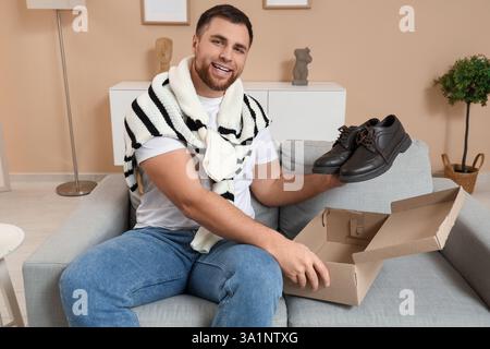 Young man with pair of stylish leather shoes on sofa at home Stock Photo