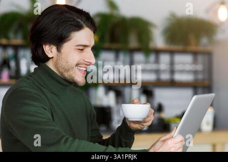 Cheerful man using digital tablet and drinking coffee Stock Photo