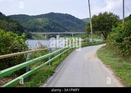 Sunchang County, South Korea - October 4, 2021: A winding section of the Seomjingang Bike Path follows the Seomjin River, with a bridge in the distanc Stock Photo