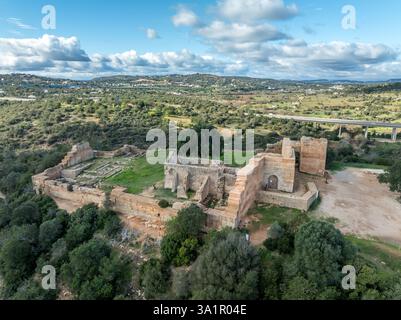 Stone ramparts & crenellated walls define Paderne Castle's medieval architecture, a historic Portuguese fortress against a blue sky Stock Photo