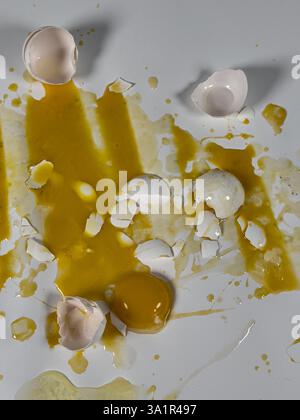 Broken eggs on white background create abstract vertical background plate. Stock Photo