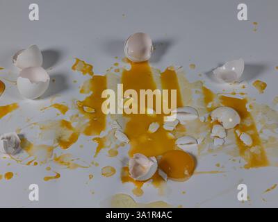 Messy cracked eggs on white background create abstract background plate. Stock Photo