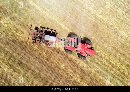 tractor working in a field on bright sunny day. concept of work in a fields and agriculture industry. Plowing the land with plow using a tractor. harv Stock Photo