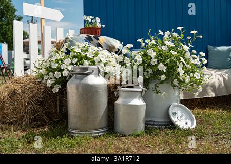 Rural view with old and worn steel milk jug milk can on the grass , next to the traditional wooden cottage in Village in Poland Stock Photo