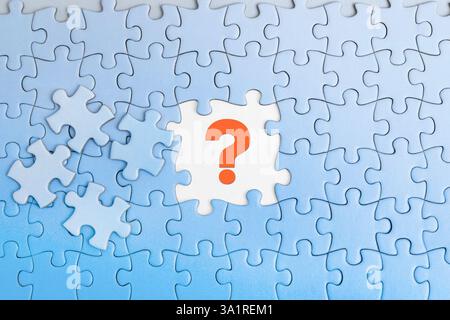 A blue background displays puzzle pieces, with a red question mark highlighted, representing the search for answers and solutions Stock Photo