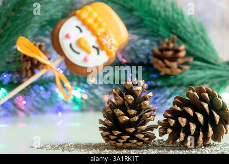 New Year's gingerbread on a stick and cones close-up on the background of Christmas tree branch with cones Stock Photo