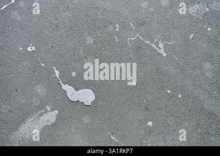 Close-up of concrete wall with white paint splashes and rough texture. Background for construction and renovation concep Stock Photo