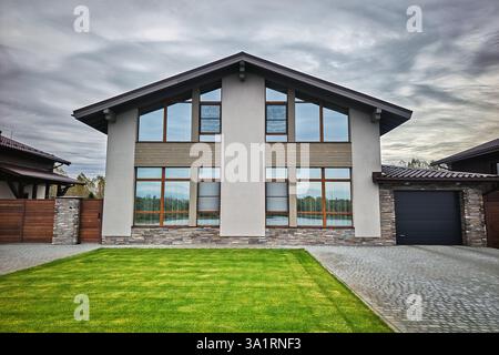 Construction of a new two-storey house with modern design and architecture with lots of glass windows and beautiful landscaping. Luxury expensive coun Stock Photo