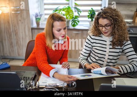 Two female colleagues at a desk working together on business report Stock Photo