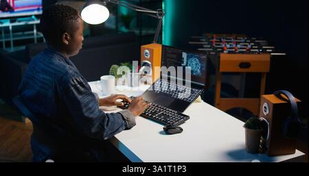 AI expert writes code on laptop in apartment office using Java programming languages. Artificial intelligence programmer remotely working on fixing database errors while working from home, camera B Stock Photo