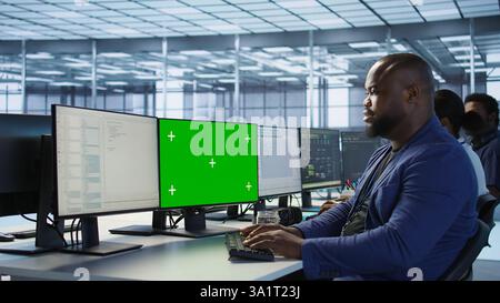Engineer using green screen computer in server room, developing disaster recovery plans ensuring minimal downtime. Data center worker looking at mockup PC, monitoring performance, camera A Stock Photo