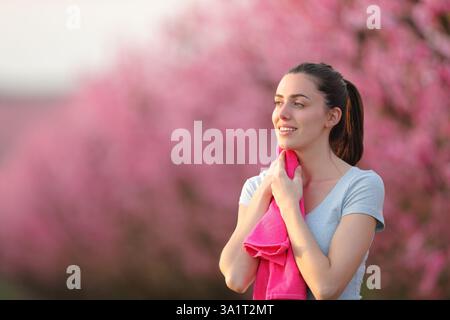 Woman drying sweat with a towel looking away after doing sport in nature Stock Photo