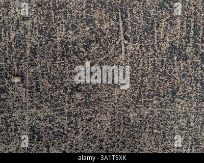 Closeup view of a textured dark gray concrete surface features beige speckles small holes and fine cracks Stock Photo