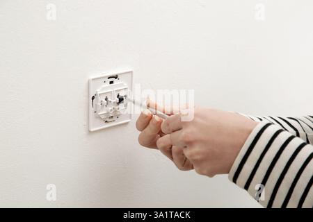 Electrical Outlet Repairing and Assembling - home improvement concepts. Master electrician installs a socket in the house. DIY home project. Stock Photo