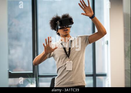 Man with Afro hairstyle using vr headset interacting with virtual environment Stock Photo