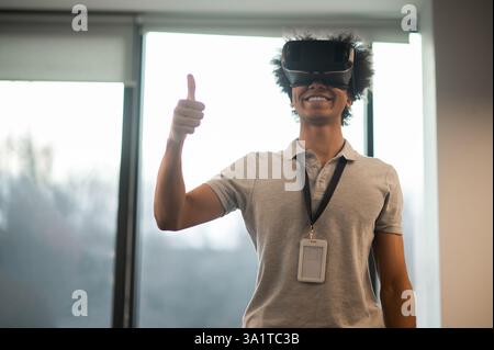 Man with Afro hairstyle using vr headset interacting with virtual environment Stock Photo