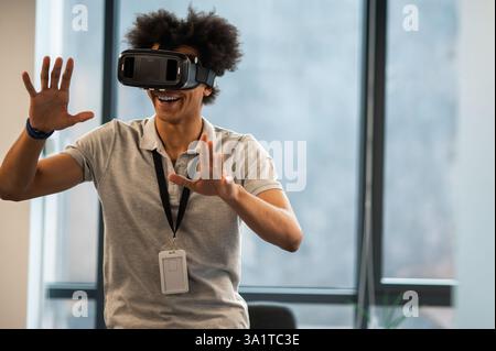 Man with Afro hairstyle using vr headset interacting with virtual environment Stock Photo