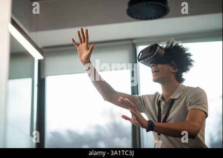 Man with Afro hairstyle using vr headset interacting with virtual environment Stock Photo