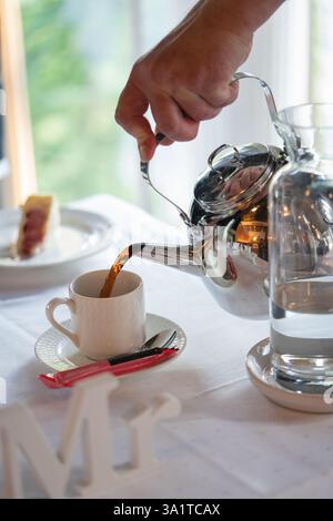 Man pouring coffee from a teapot into a cup of coffee Stock Photo