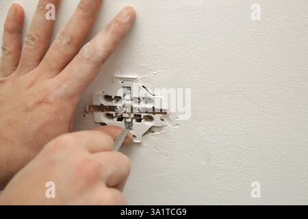 Electrical Outlet Repairing and Assembling - home improvement concepts. Master electrician installs a socket in the house. DIY home project. Stock Photo