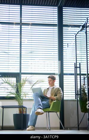 Entrepreneur in modern business lounge using laptop for online communication and task management. Stock Photo