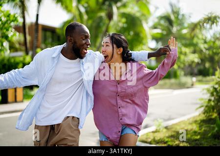 Happy interracial couple laughing together outdoors, enjoying a carefree moment of love, joy Stock Photo