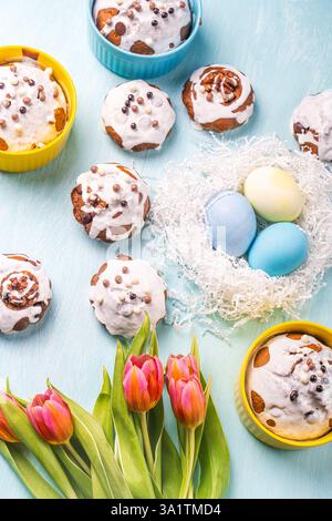 Easter cakes, painted eggs in the nest and tulips on a blue background. Flat layout. View from above. High quality photo Stock Photo