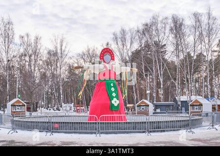 Yekaterinburg, Russia - February 26, 2025: Traditional Maslenitsa effigy in bright folk attire in snowy park. Slavic festival figure represents farewe Stock Photo