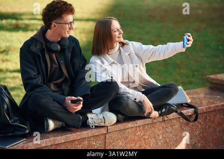 Taking a selfie. Two young students are together outdoors. Stock Photo
