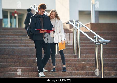 Front view, walking the stairs. Two young students are together outdoors. Stock Photo