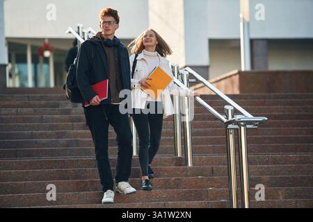 On the stairs. Two young students are together outdoors. Stock Photo