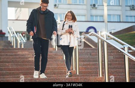 On the stairs. Two young students are together outdoors. Stock Photo