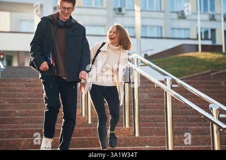 On the stairs. Two young students are together outdoors. Stock Photo