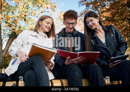 Three young students are outside the university outdoors. Stock Photo