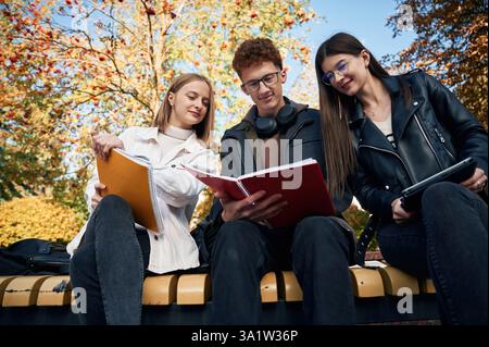 Three young students are outside the university outdoors. Stock Photo