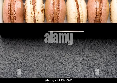 Macaroons in a black cardboard box on a dark background. Stock Photo