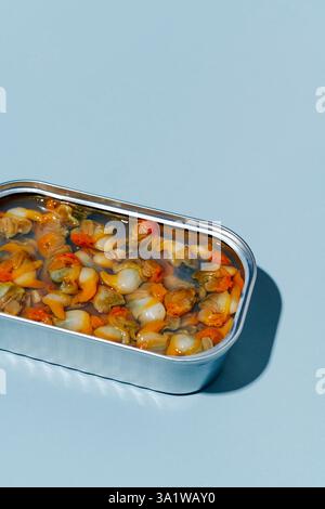 closeup of an open can of tinned cockles on a light blue background with some blank space on top Stock Photo