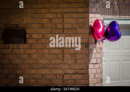 Collored Party balloons and mailbox  on the exterior of a brick house in the bright sunlight Stock Photo