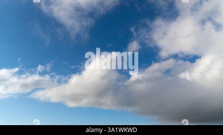 A vast cloudscape of fluffy white clouds stretching across a deep blue sky, creating a serene and airy atmosphere. Stock Photo