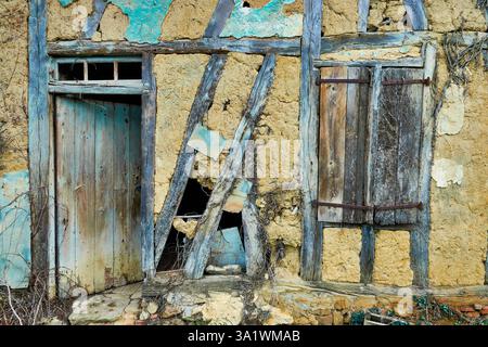 Old Weathered House Wall with Rustic Wooden Door and Broken Window Stock Photo