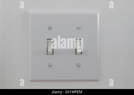white Double house light switch platein OFF position on a white wall Stock Photo