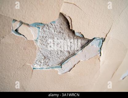Multiple layers of different paint on an old wall, visible after a piece of plaster has peeled off Stock Photo
