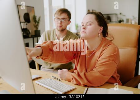 Medium close up of two tired coworkers checking codes on computers screen while working together in office Stock Photo