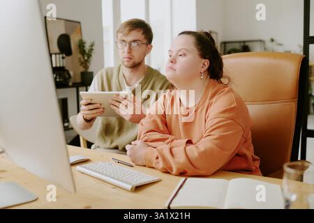 Medium close up of two highly qualified Caucasian IT specialists sitting on computers chair and working with documents together Stock Photo
