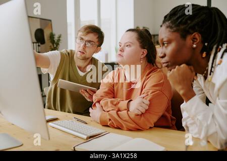 Medium close up of concentrated biracial team looking at monitor while working with codes together Stock Photo