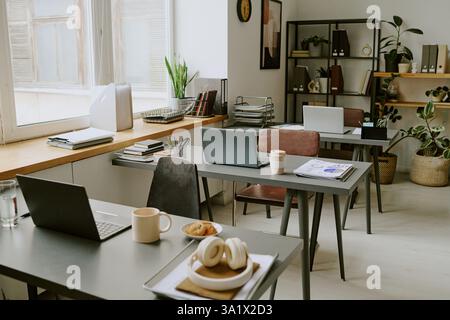 High angle shot of modern office with several workplaces with workers belongings and digital devices on desks Stock Photo