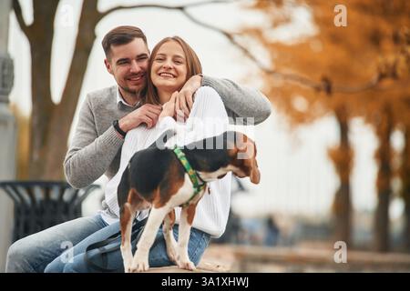 Smiling, having fun. Lovely couple are with their cute dog outdoors. Stock Photo