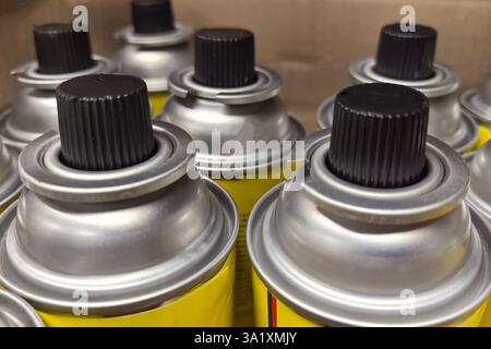 Several brightly colored gas cans are lined up on a shelf in a workshop. Their metallic tops shine under the light, indicating they are ready for vari Stock Photo