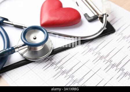 Cardiology. Cardiogram, clipboard, stethoscope and red decorative heart on table, closeup Stock Photo